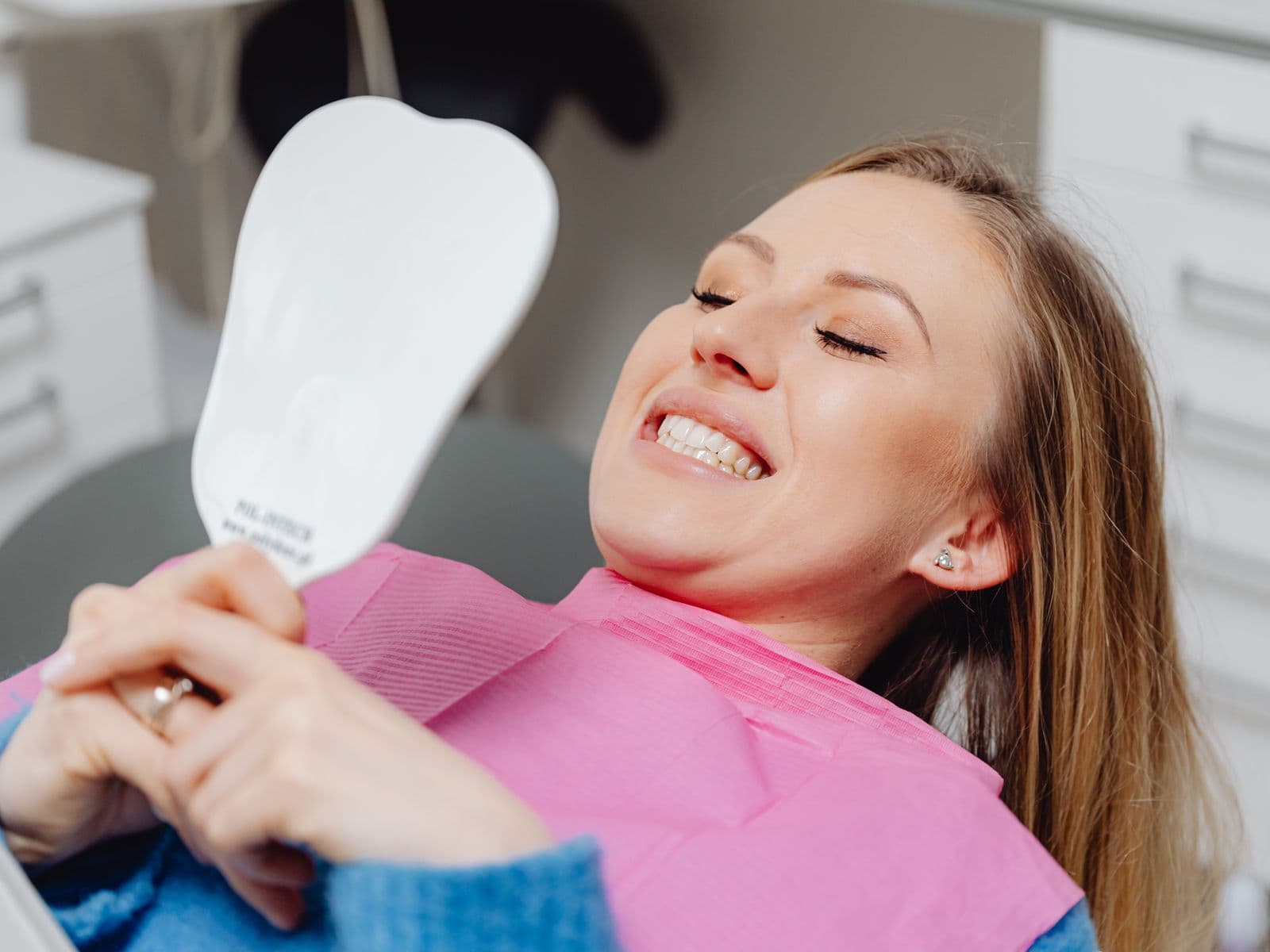 A patient admiring her brighter smile after teeth whitening